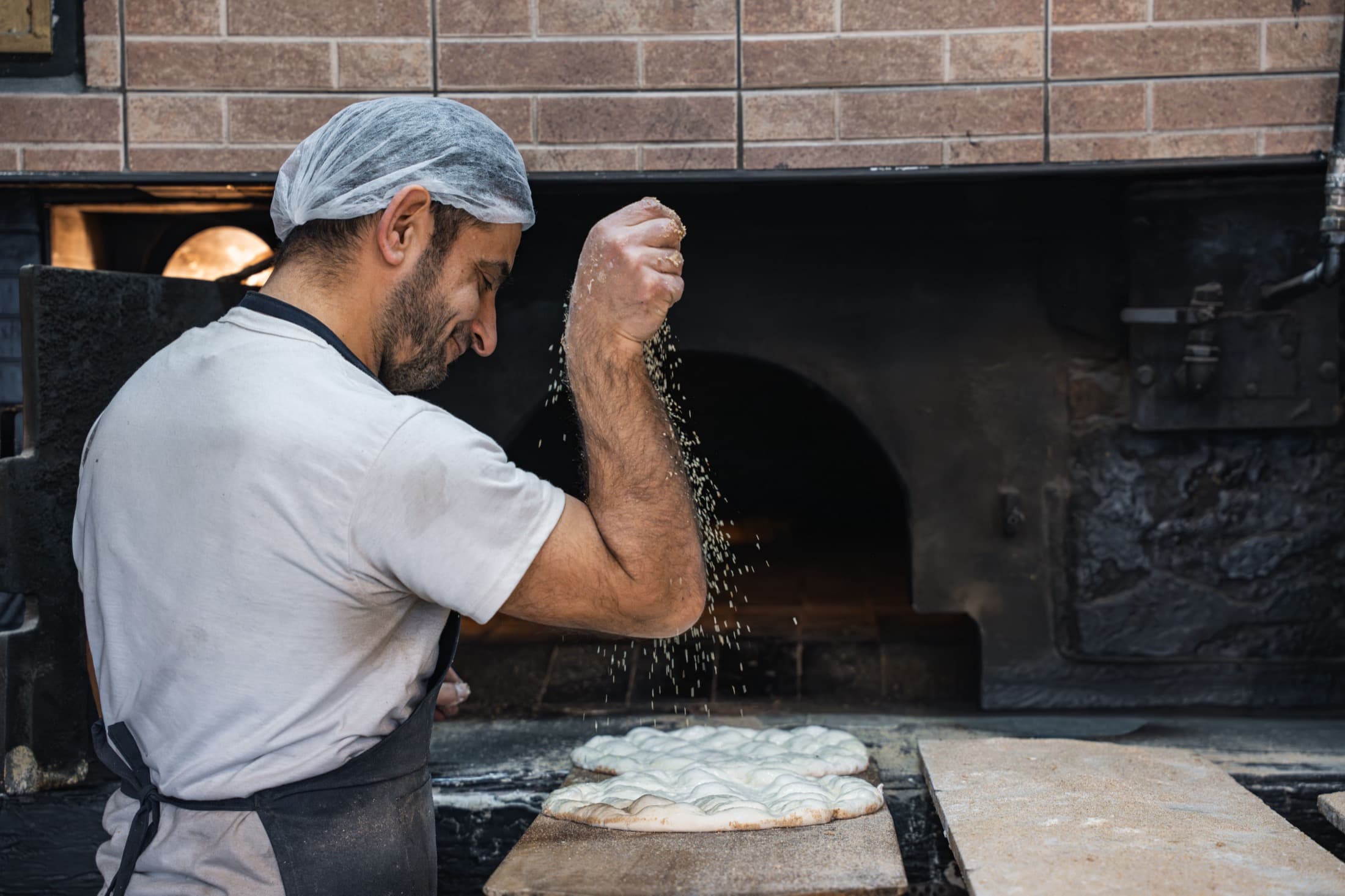 Un boulanger farine son plan de travail devant le four