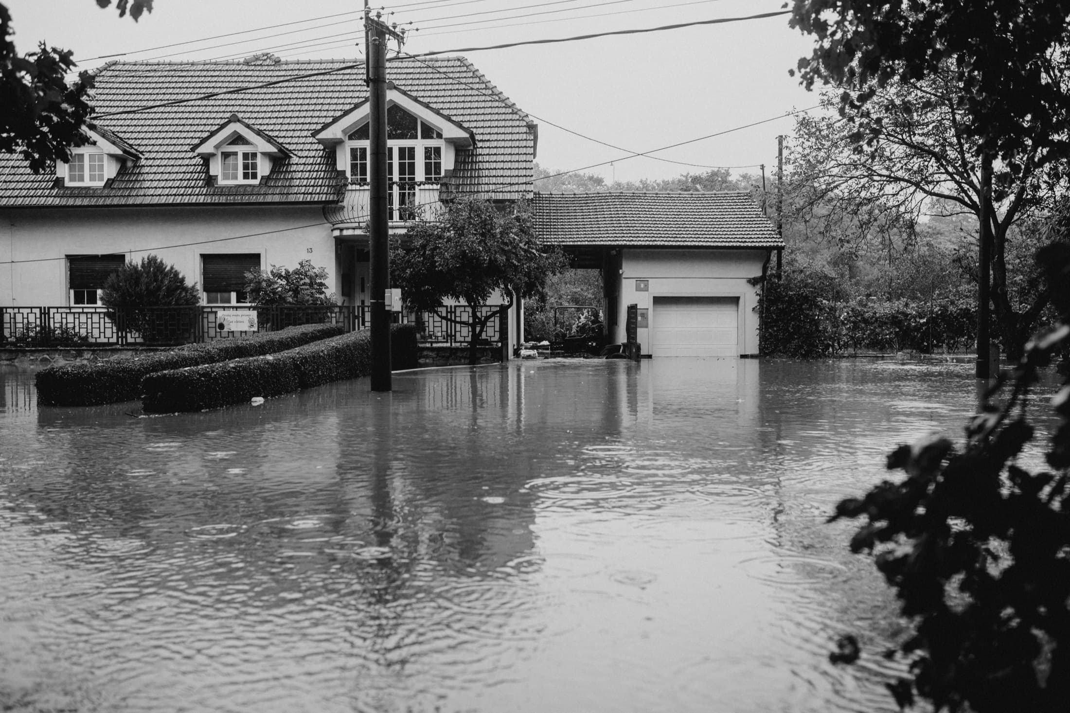 Une rue résidentielle inondée, en noir et blanc