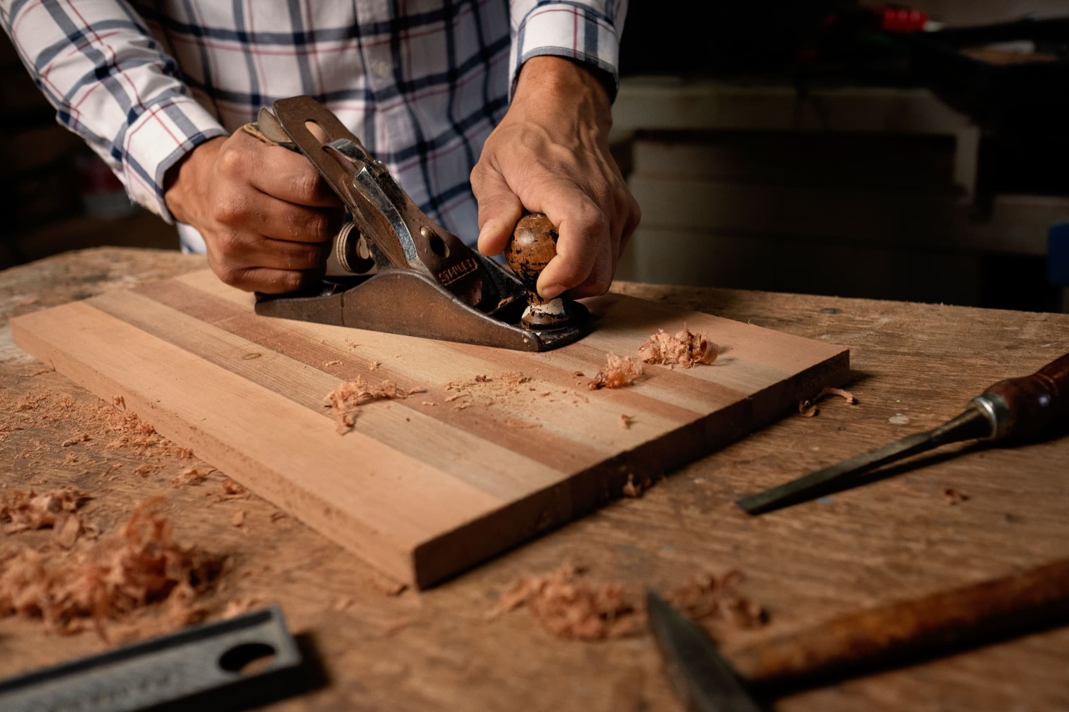 Les mains d'un menuisier poussent un rabot sur une planche