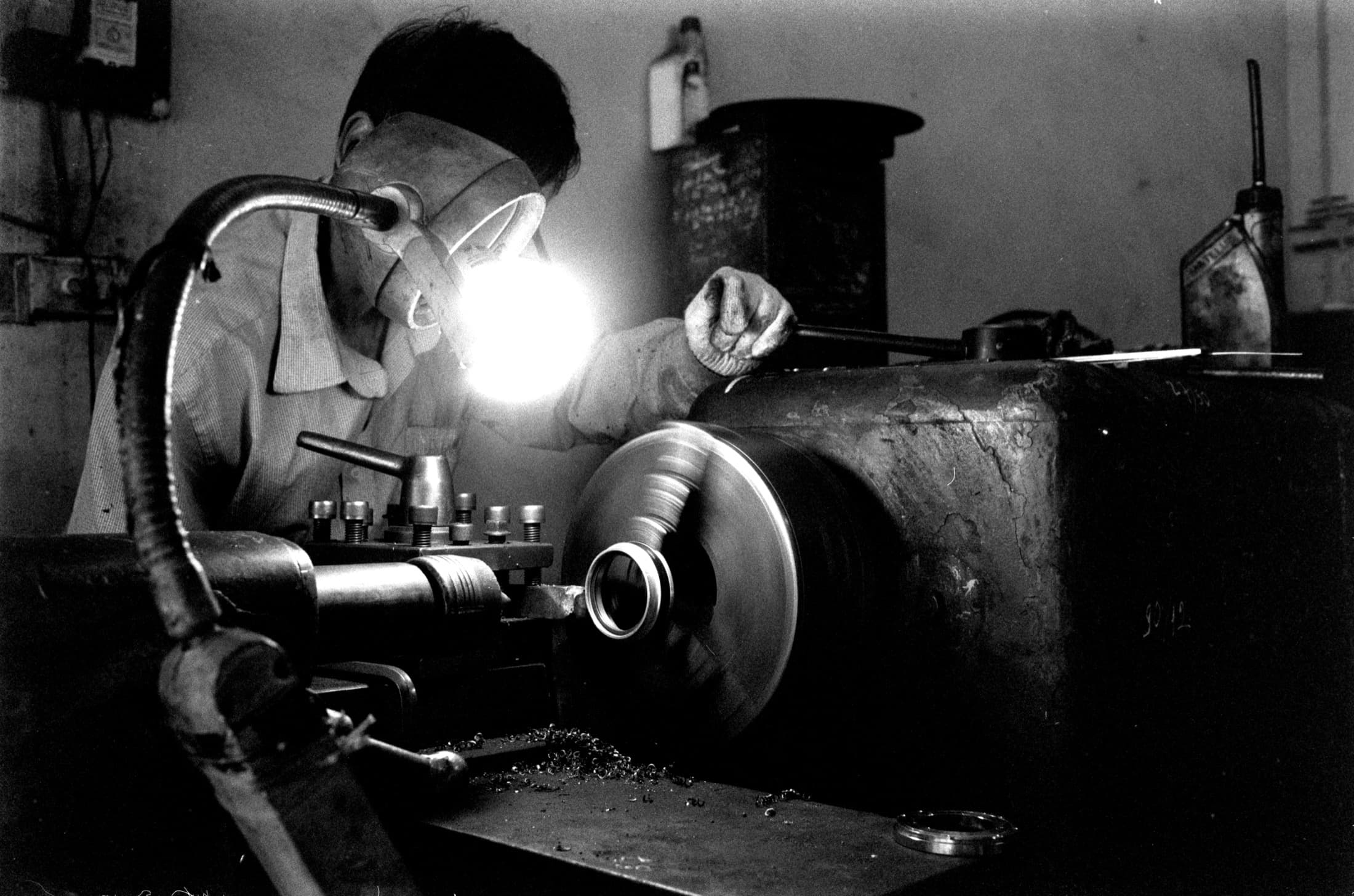 Un tourneur au travail sur sa machine, dans un atelier
