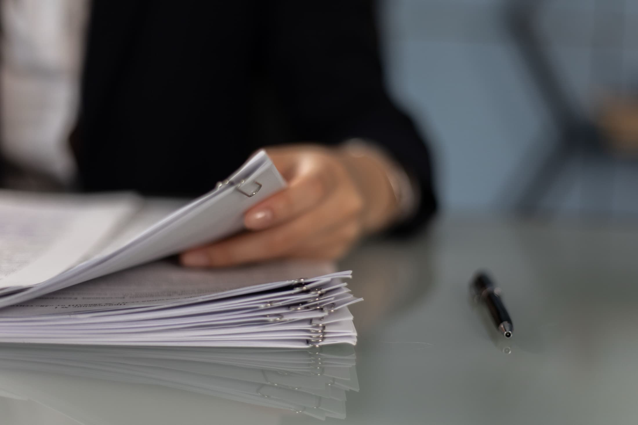 Les mains d'une juriste feuillettent un dossier épais