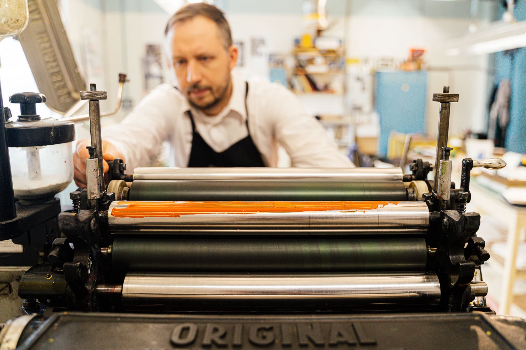 Un imprimeur règle les rouleaux de sa presse