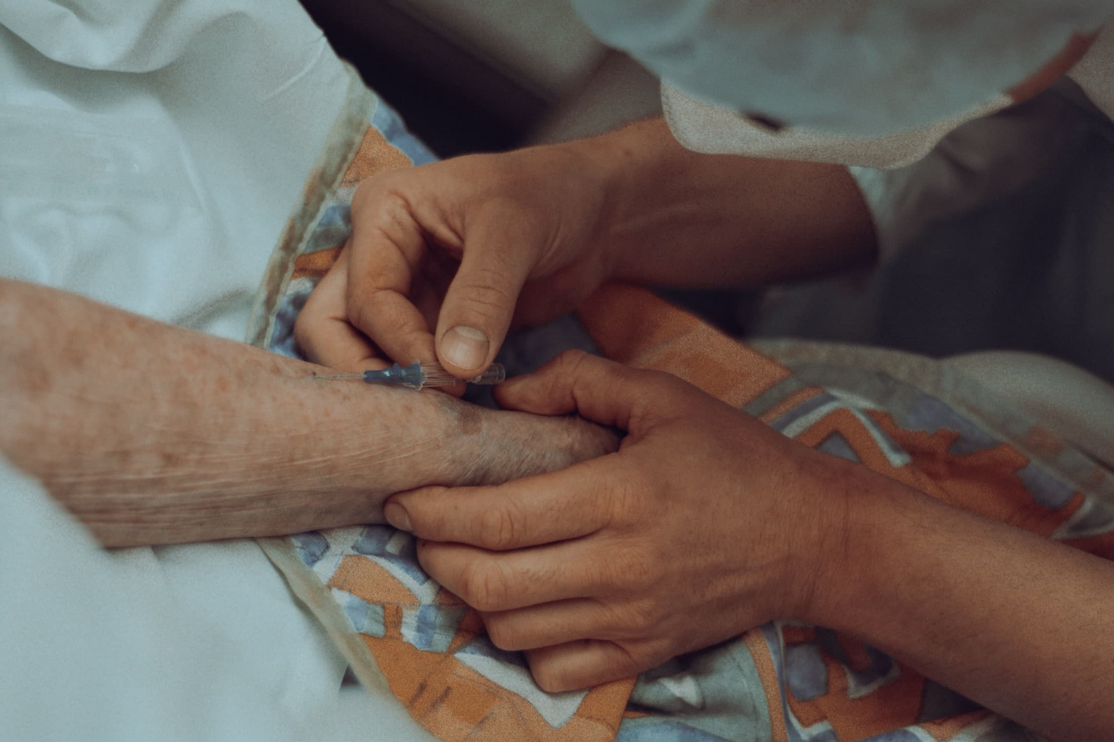 Les mains d'un soignant tiennent celles d'un patient âgé