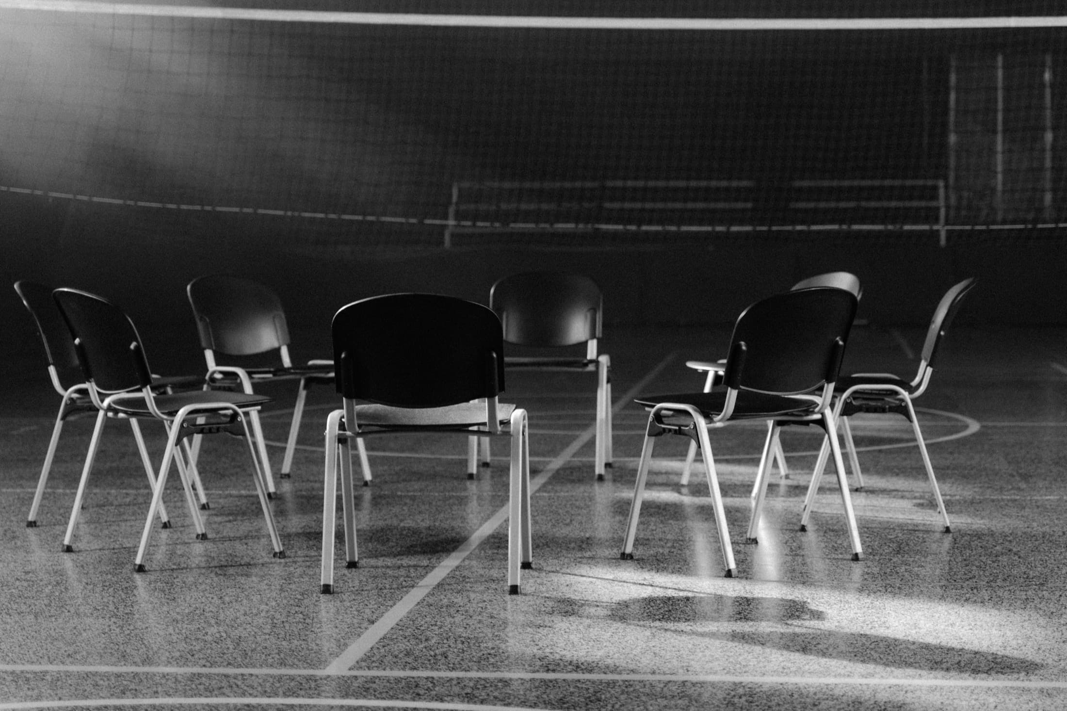 Des chaises vides disposées en cercle dans une salle polyvalente