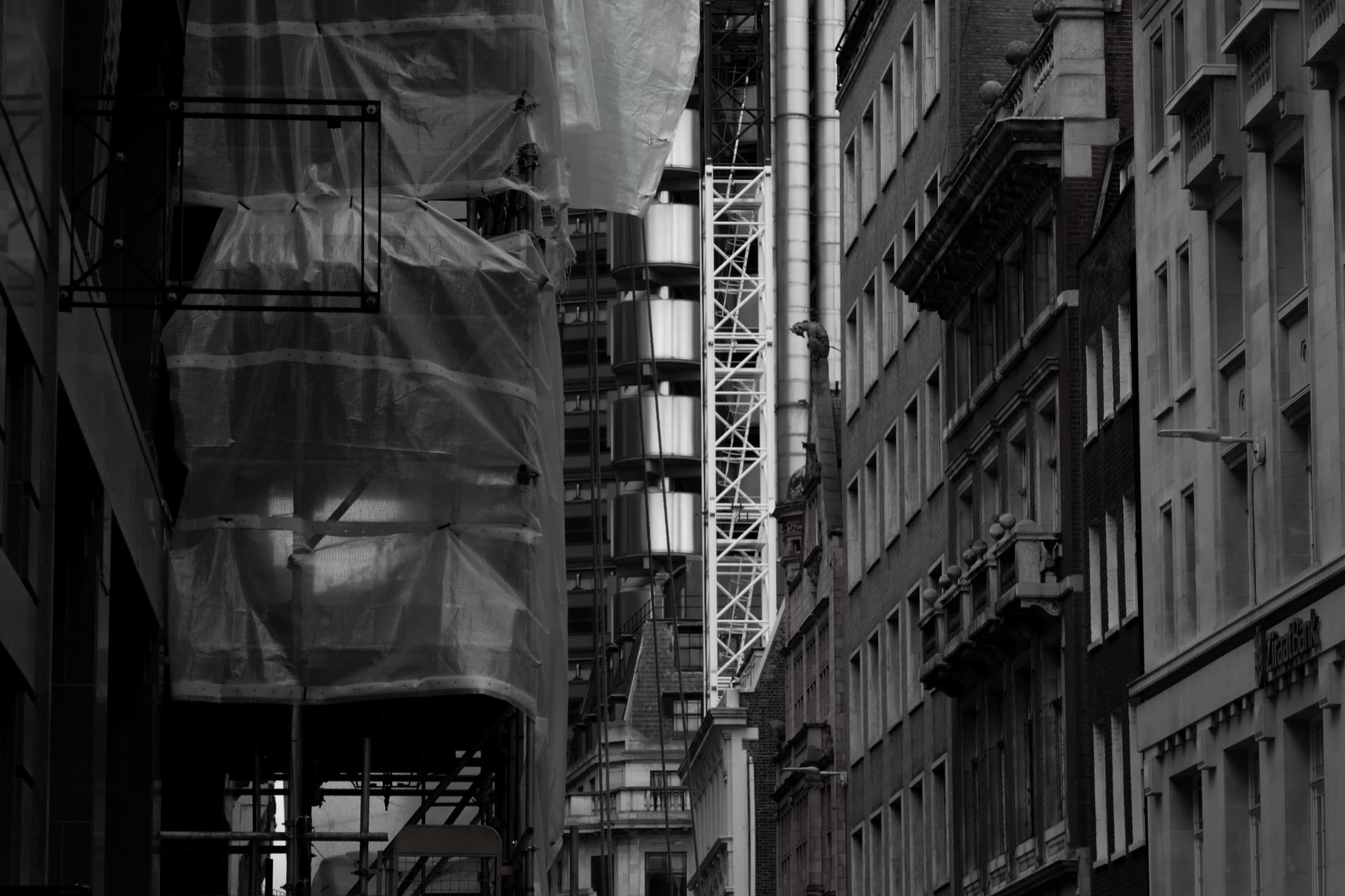 Une rue étroite bordée d'échafaudages, en noir et blanc