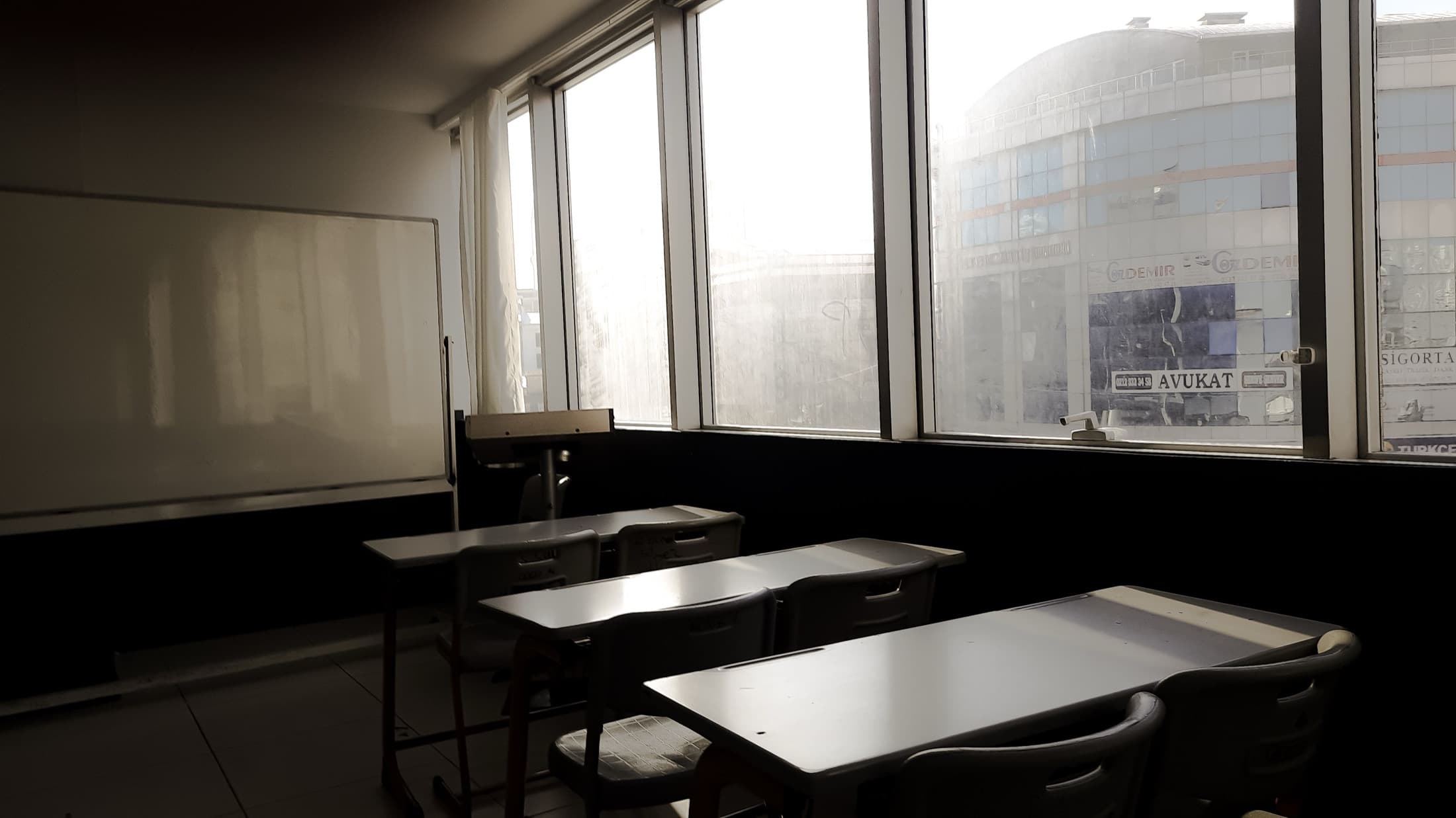 Une salle de travail vide, tables alignées devant les fenêtres